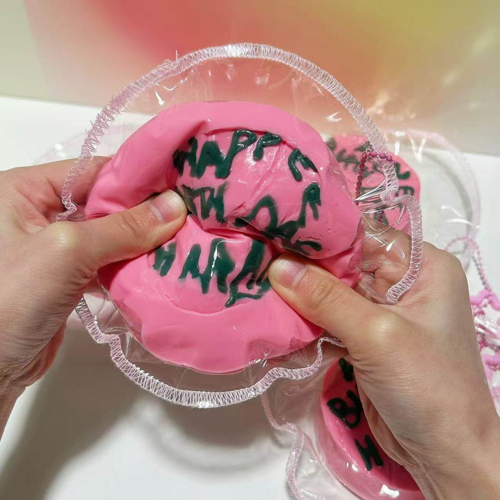 Happee Birthdae Cake squishy toy held in hand for scale
