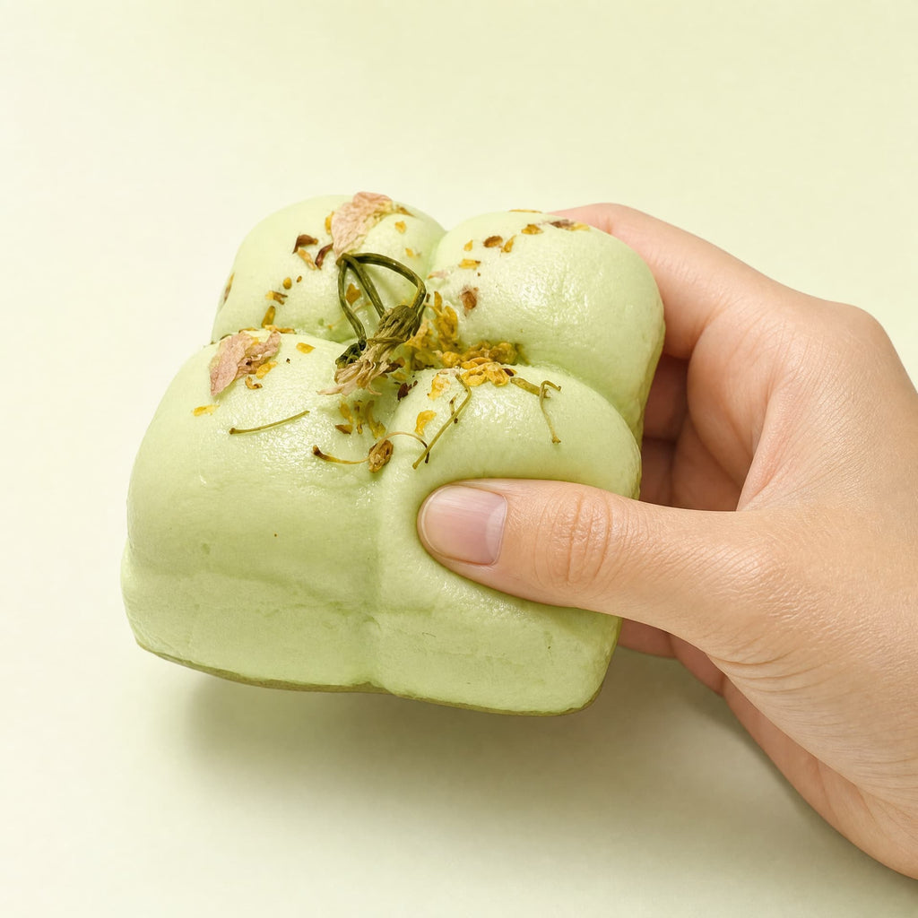 Squidgy Taba Cakes squishy toy, matcha flavor, held in one hand being squeezed