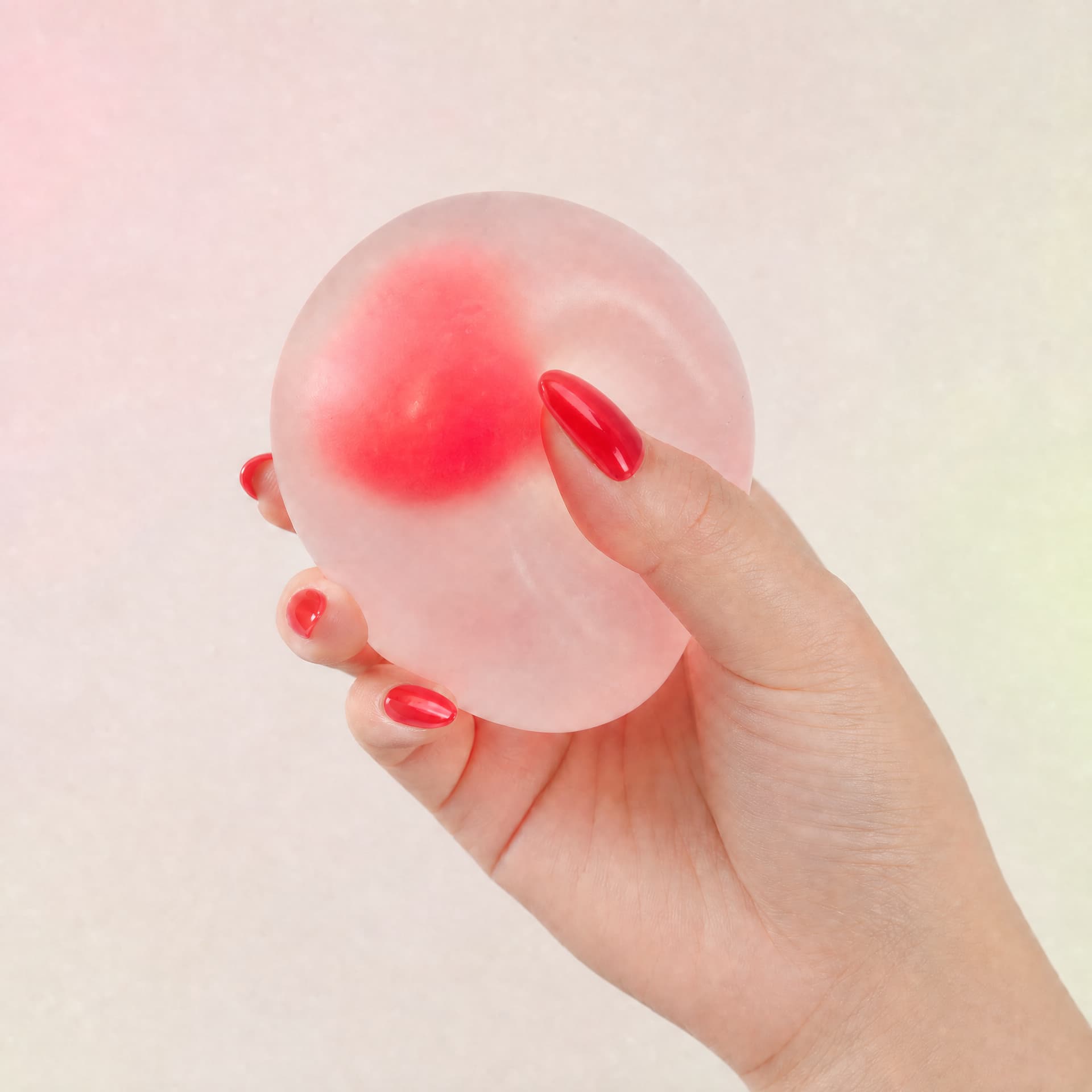 Strawberry Mochi Squeeze toy, held in hand being squeezed